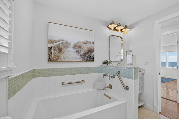 Clean, inviting bathroom with a full bathtub and thoughtfully designed coastal finishes.