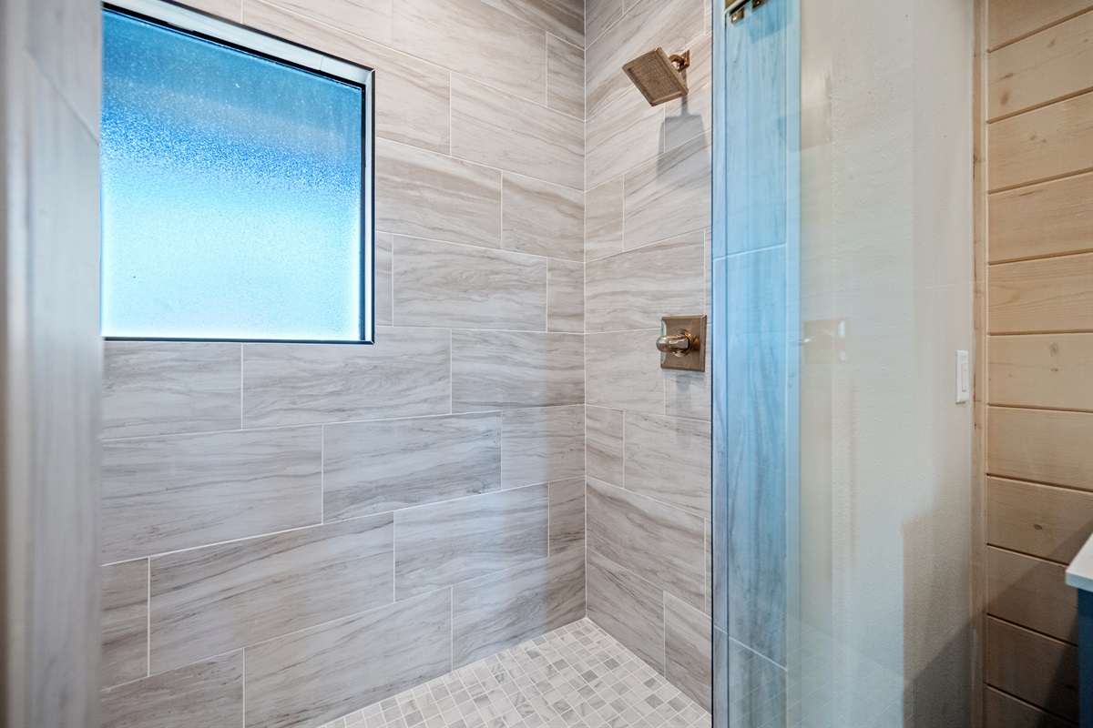Walk-in shower with stone tile accents.