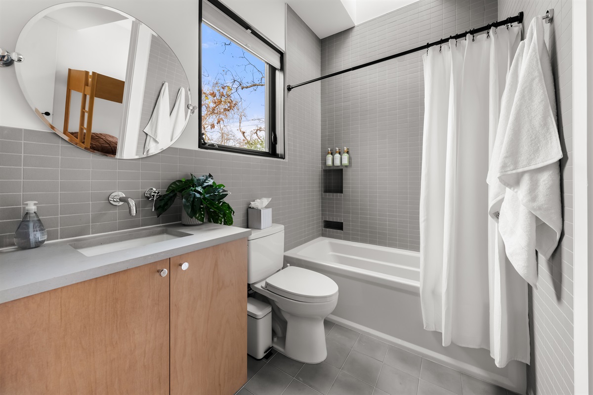 Bright and inviting full bathroom with a shower/tub combo, modern vanity, and plenty of natural light—ideal for guests to unwind and refresh comfortably.