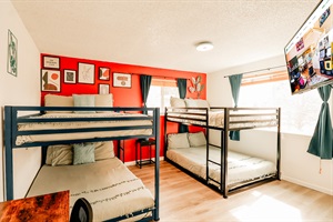 A bold red wall sets a vibrant backdrop for a sturdy bunk bed, promising tales of laughter, whispers after dark, and the sweet dreams of childhood adventures
