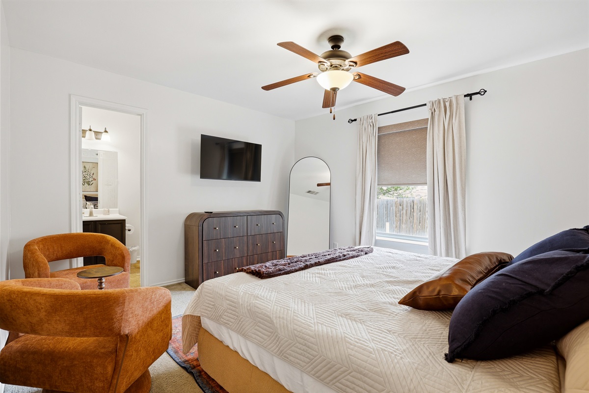 King primary bedroom with a ceiling fan, soft bedding, and private ensuite access. Spacious layout with closet storage and warm, welcoming decor throughout.
