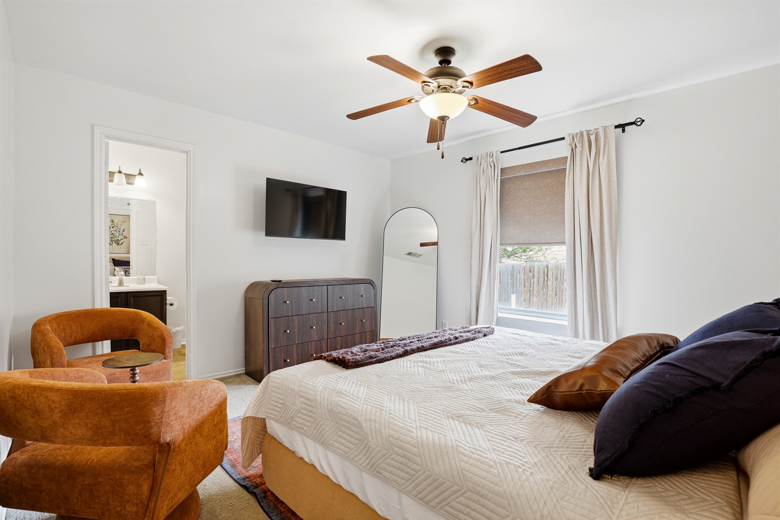 King primary bedroom with a ceiling fan, soft bedding, and private ensuite access. Spacious layout with closet storage and warm, welcoming decor throughout.