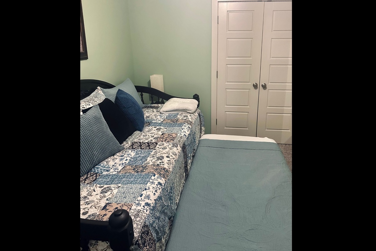 Third bedroom featuring a twin daybed with pull-out trundle that elevates to matching height, offering flexible sleeping arrangements.