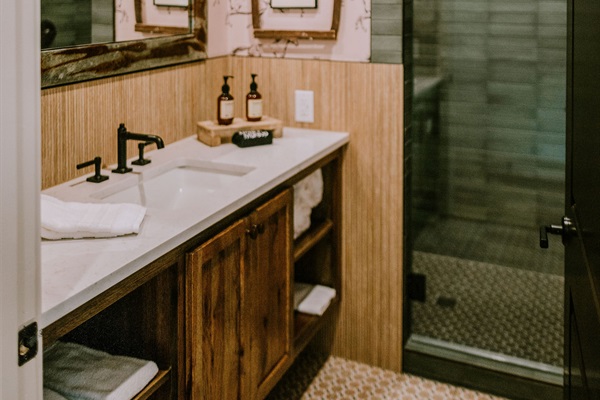 Private en-suite bathroom at Rancher's Rest &mdash; designer vanity, walk-in tile shower, and modern Western finishes at Gaines Ranch on the Square.