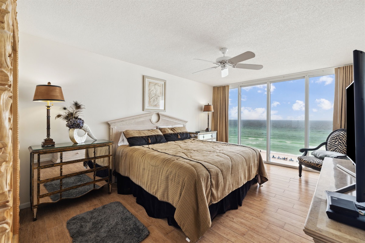 Master king suite bedroom with floor to ceiling windows showcasing the beautiful Emerald Gulf waters, balcony access from bedroom and en suite bathroom