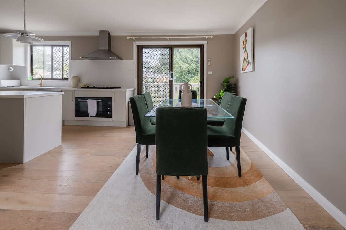 The dining area at Luna’s Sanctuary connects directly with the kitchen, balcony doors and island bench for relaxed meals at the house.