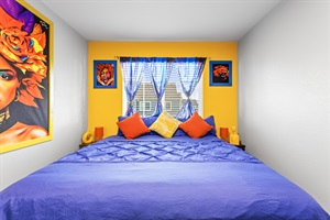 Bedroom 2 features warmth complemented by cheerful, vibrant artworks