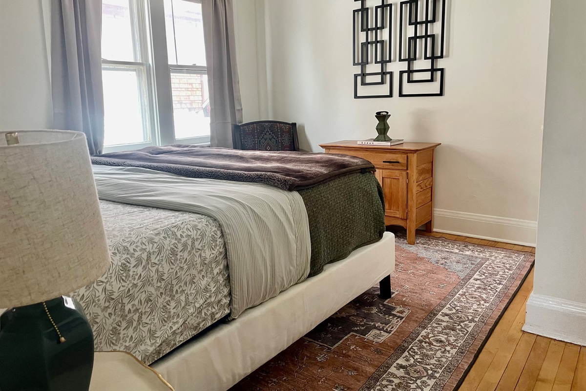 King bed with soft linens in a spacious, comfortable bedroom.