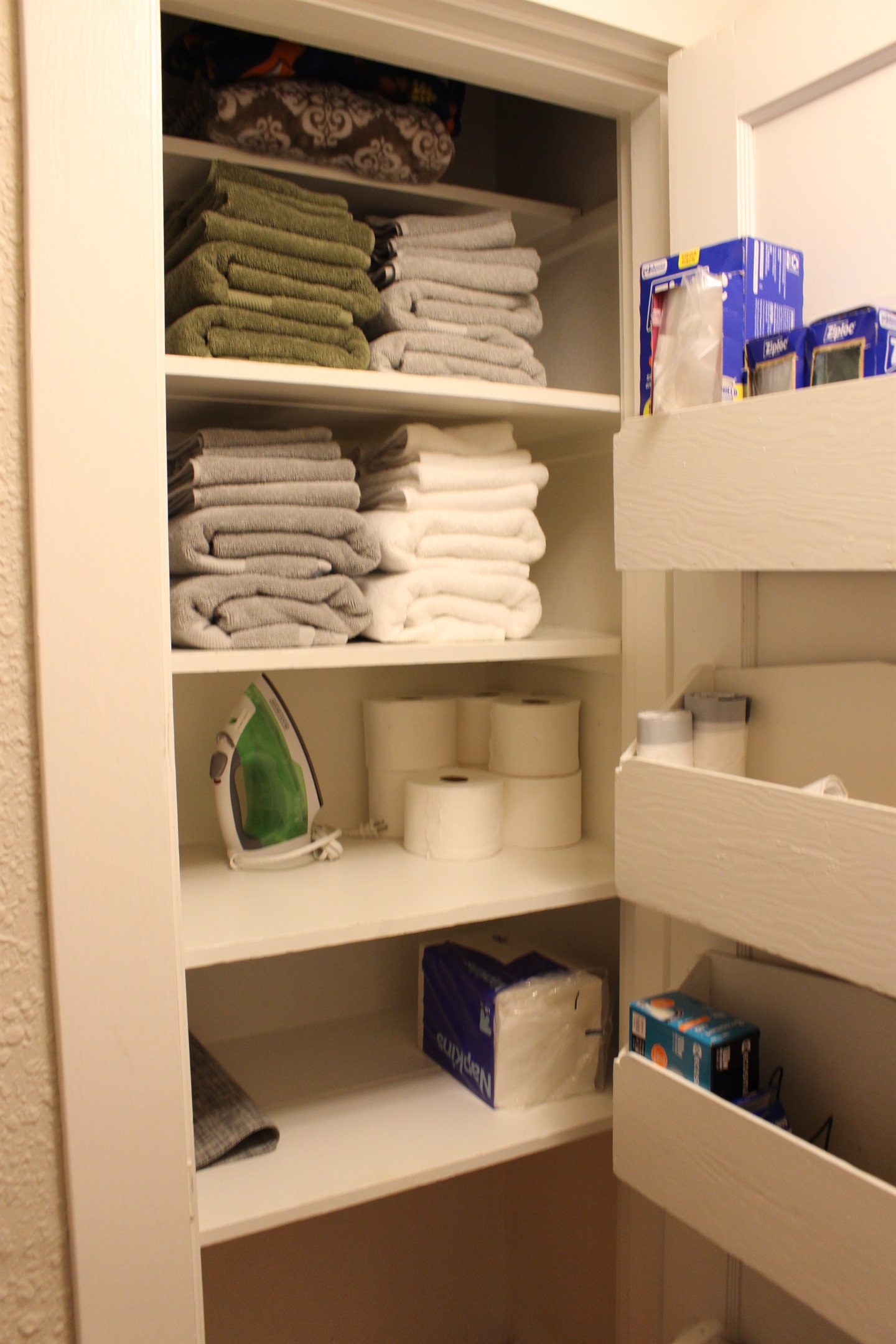 Linen closet outside bathroom complete with linens and limited cleaning supplies as well as first aid kit