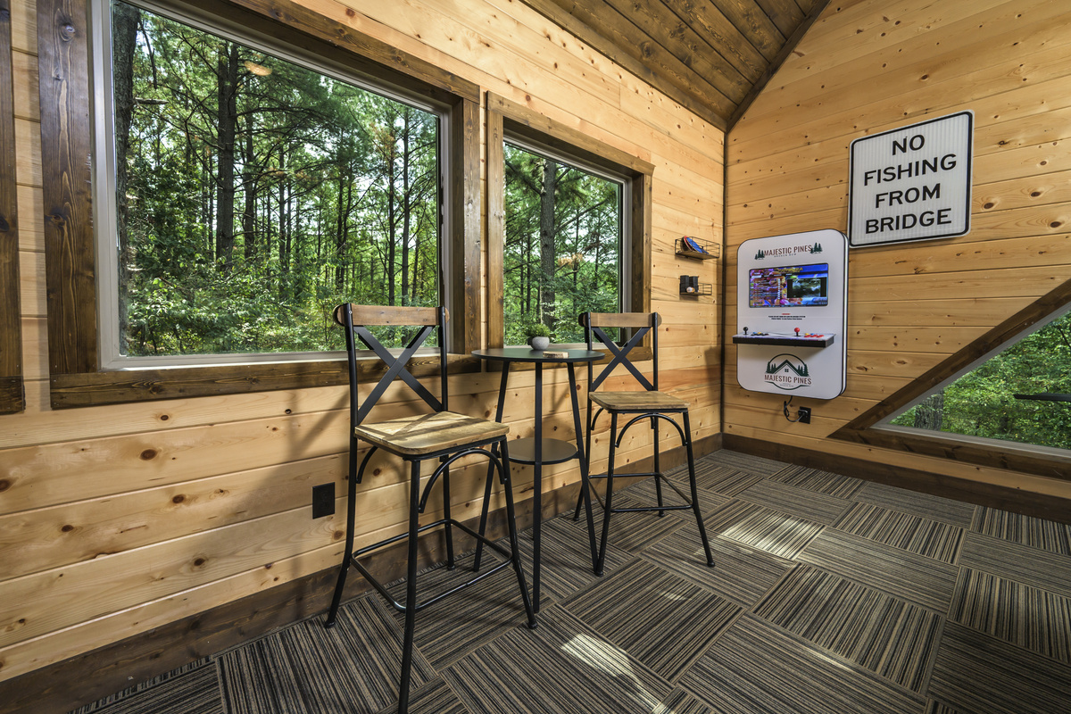 Enjoy forest views from the cozy game loft, featuring arcade fun and a charming seating area.
