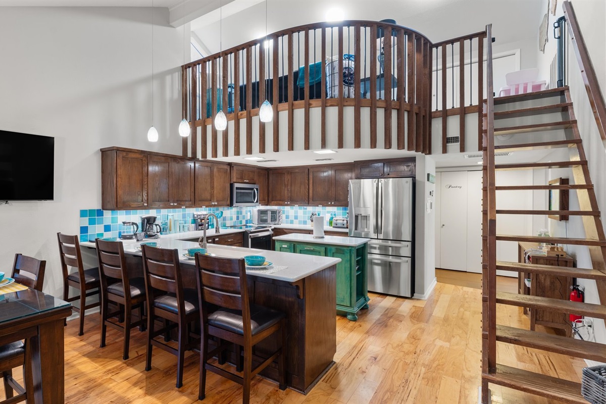 Stairs leading to the children’s play loft, a favorite spot for kids. A widened view of the kitchen is also visible. Note the stairs are steep, but there’s a baby gate at the top for safety.