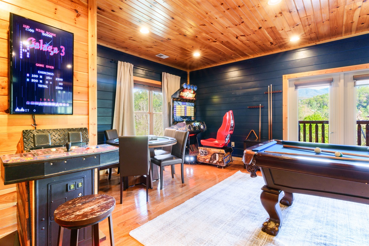 Arcade room with multiple games, card table, and pool table.
