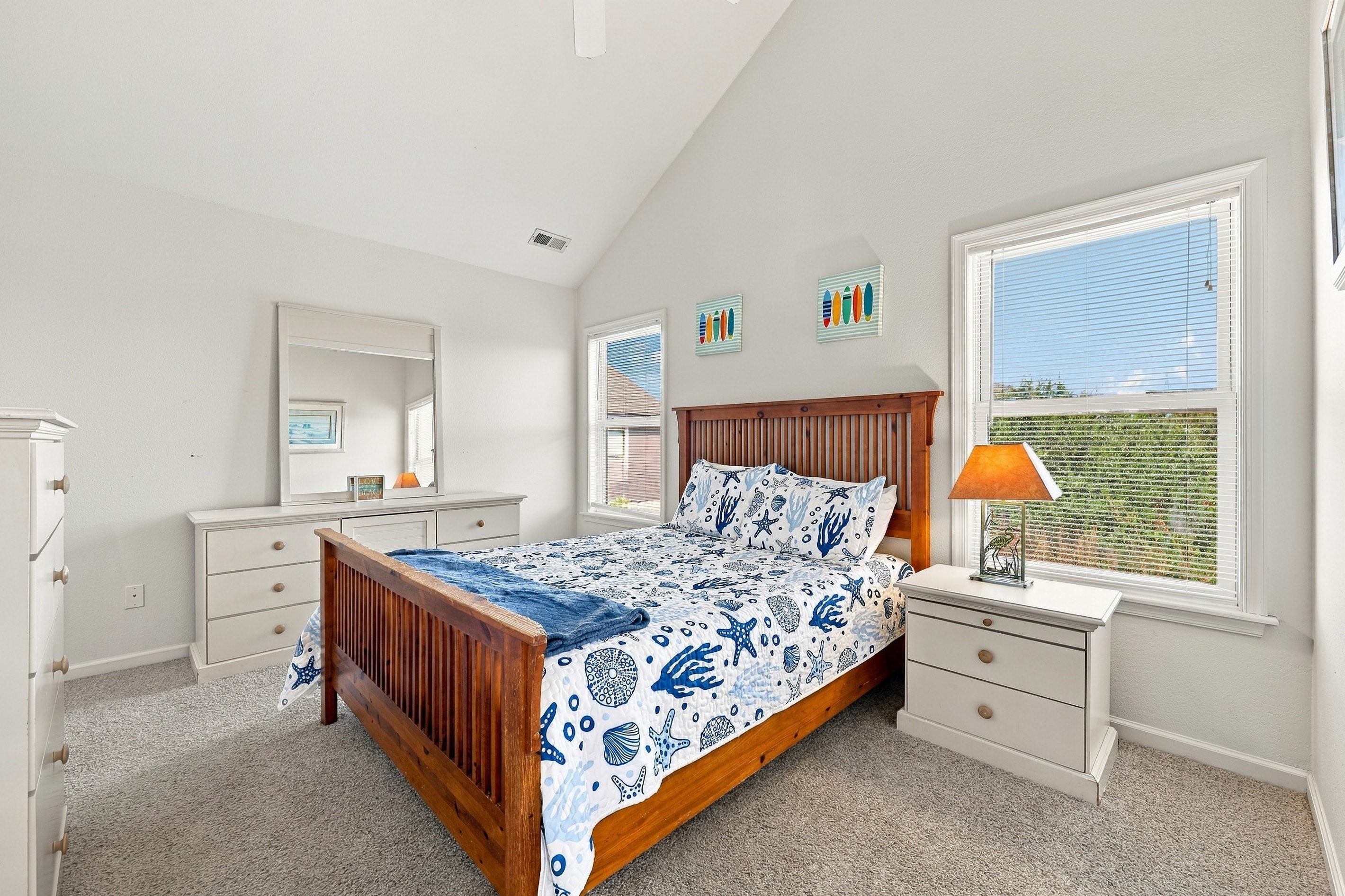 Top-floor bedroom with vaulted ceilings and cheerful coastal bedding.