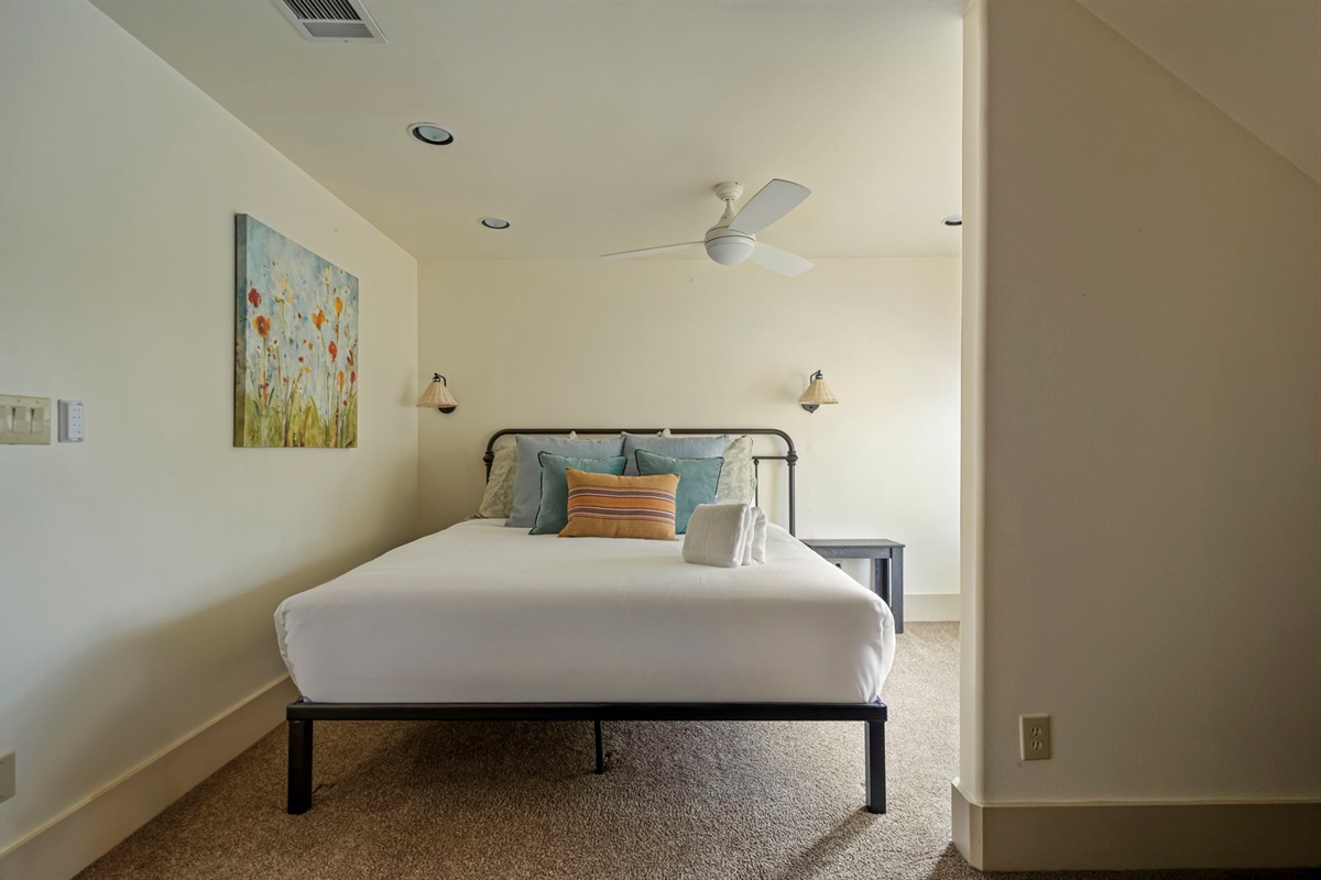A private retreat with a king-sized bed, bedside lighting, a clothes rack, and a window that brings in natural light.