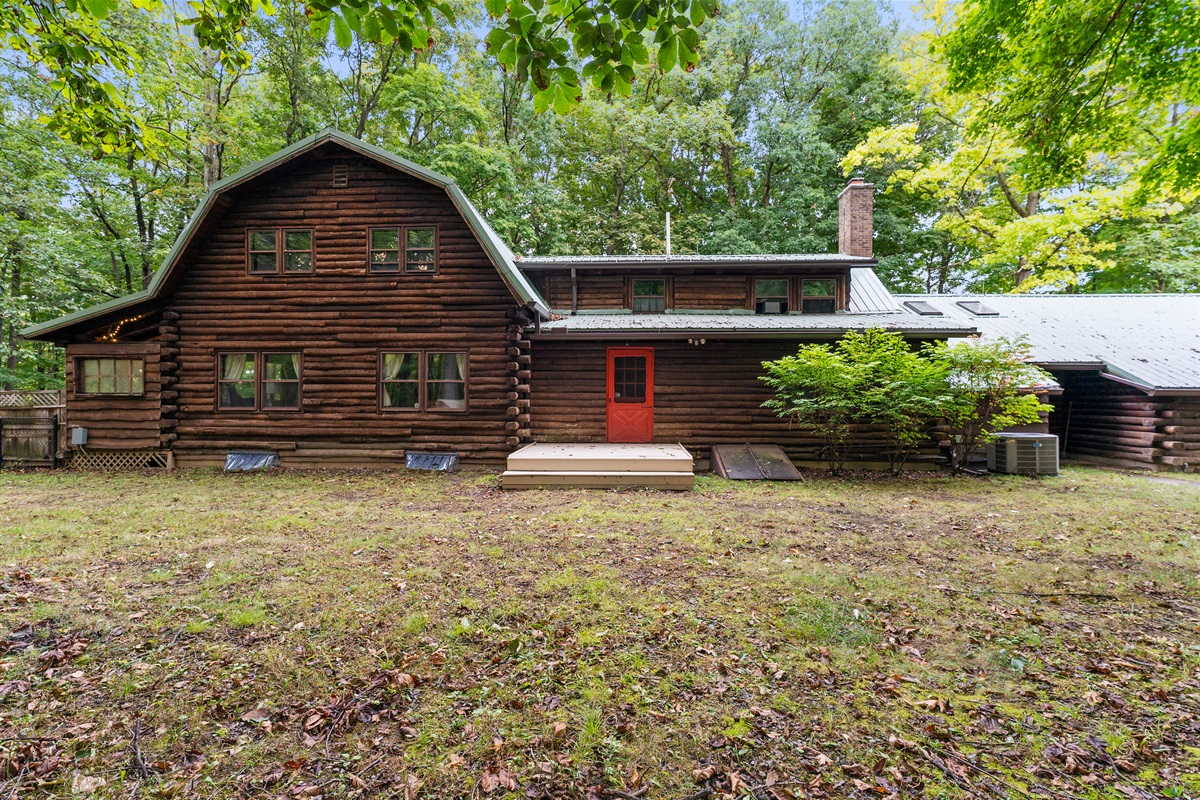 Charming log cabin retreat surrounded by nature, featuring rustic wood architecture and a welcoming red door—perfect for a cozy getaway.
