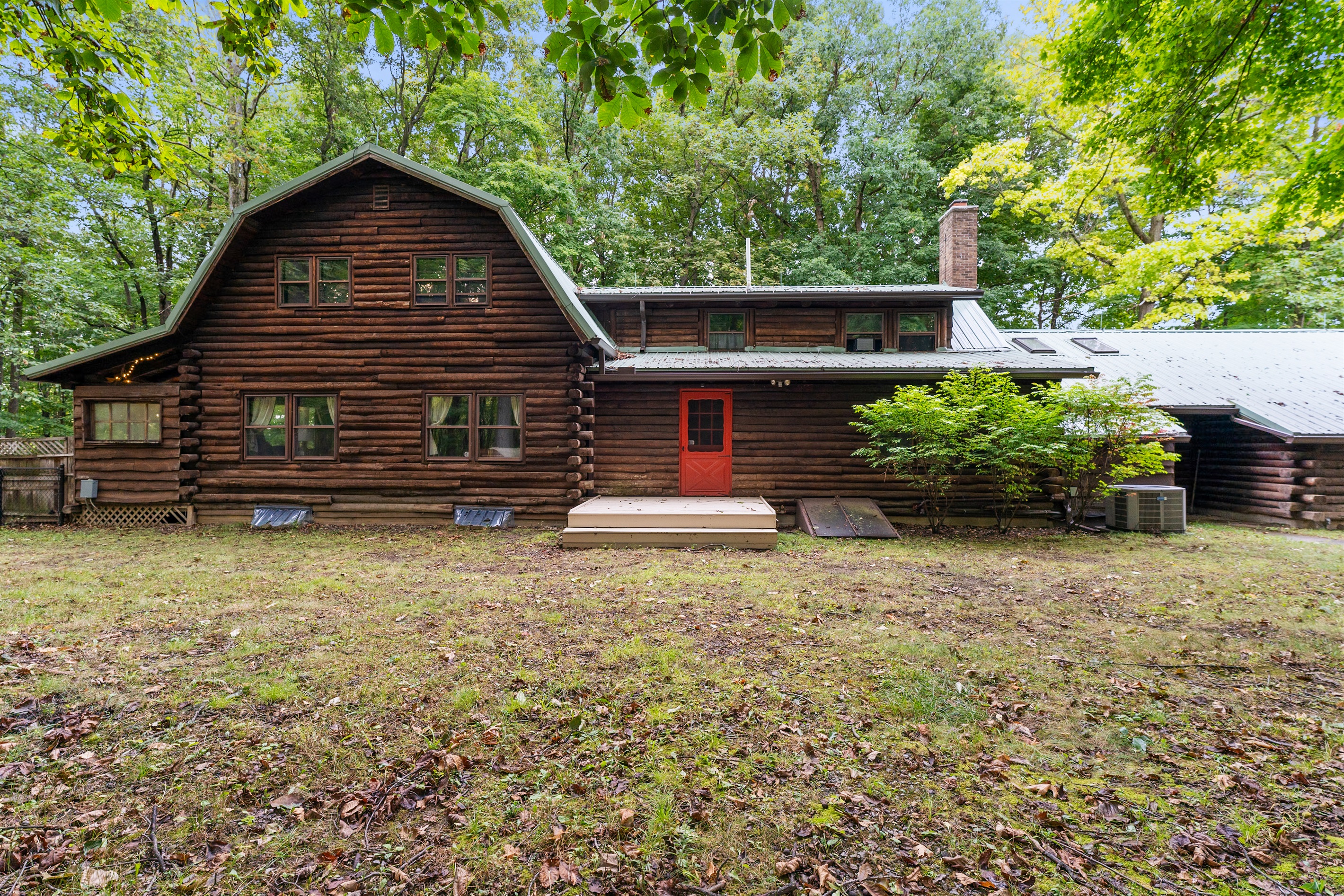 Charming log cabin retreat surrounded by nature, featuring rustic wood architecture and a welcoming red door—perfect for a cozy getaway.