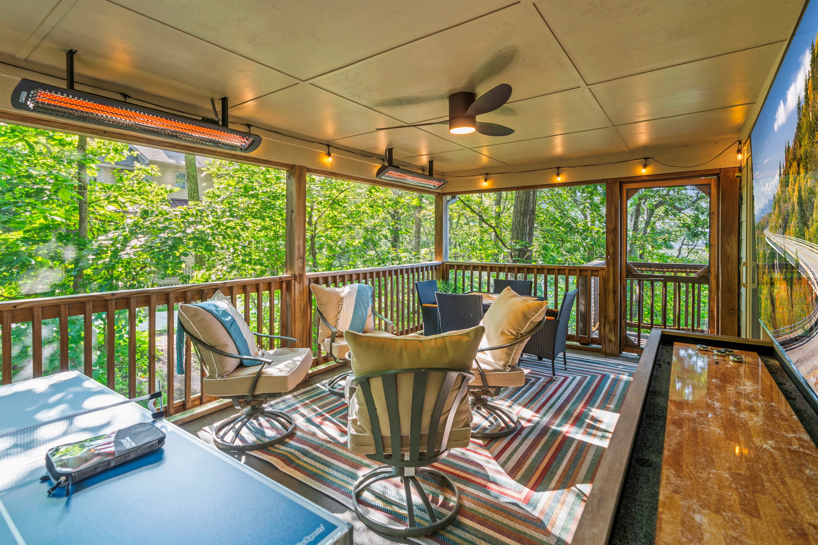 Treehouse vibes meet upscale amenities — shuffleboard, ping pong, and radiant warmth make this screened porch a year-round haven.