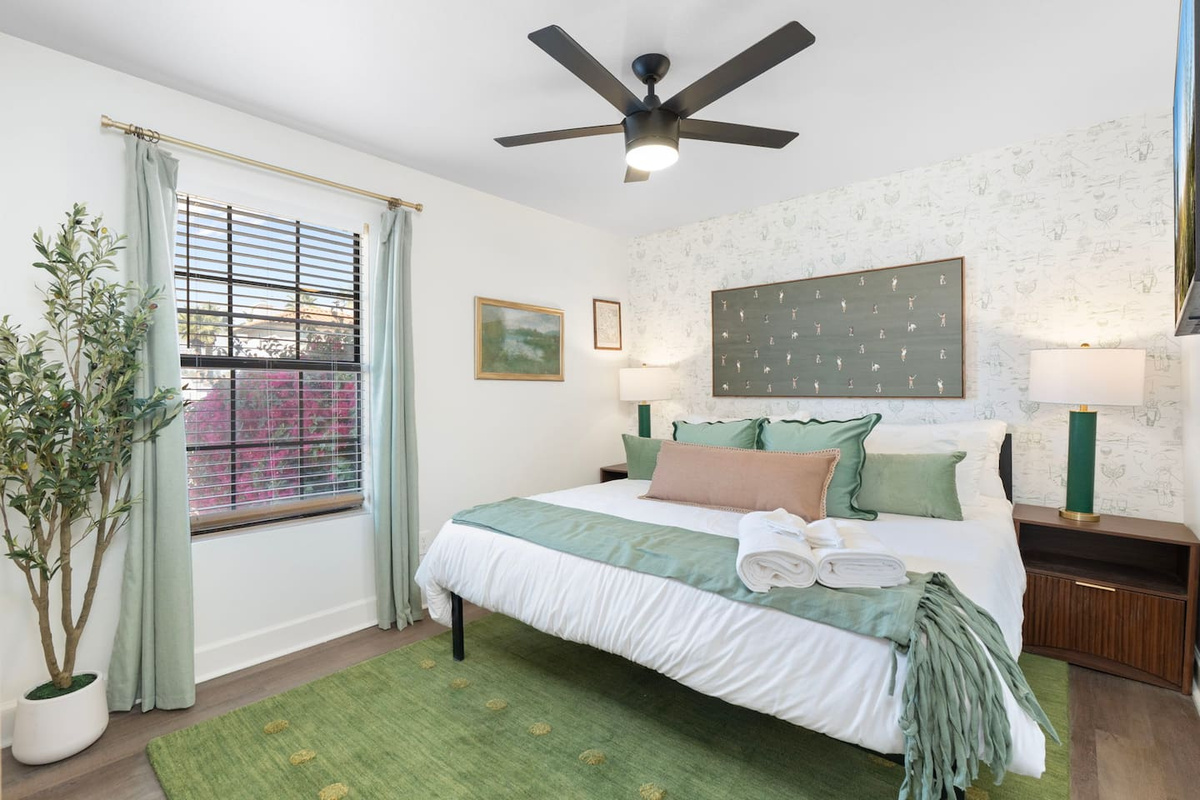 Serene guest bedroom with soft green palette, natural light, and layered textures—a peaceful retreat for rest and relaxation.
