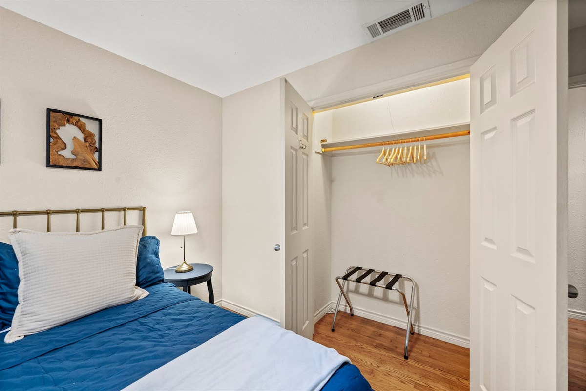 Spacious closet with hangers and luggage rack, plus cozy bedside lighting—designed for comfort and convenience.