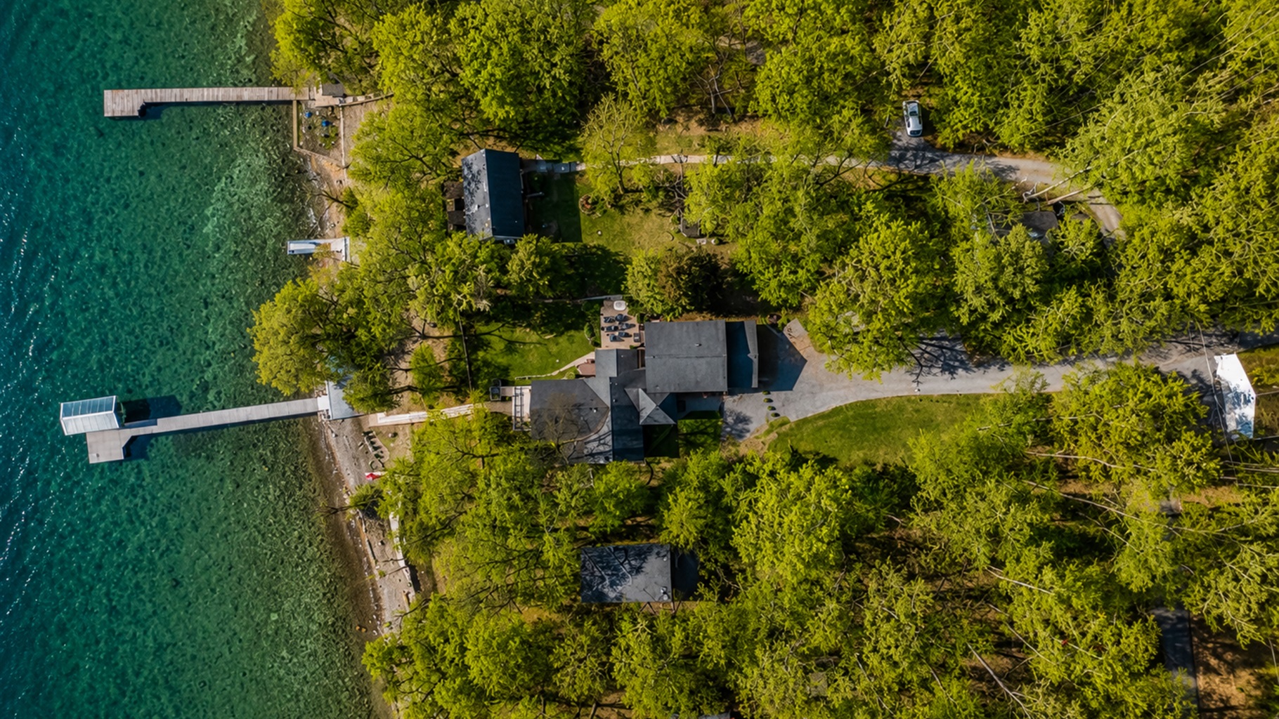 Discover the breathtaking layout of this lakeside retreat, captured from above. It features multiple cabins and private docks nestled among trees, perfect for both adventure and relaxation. 