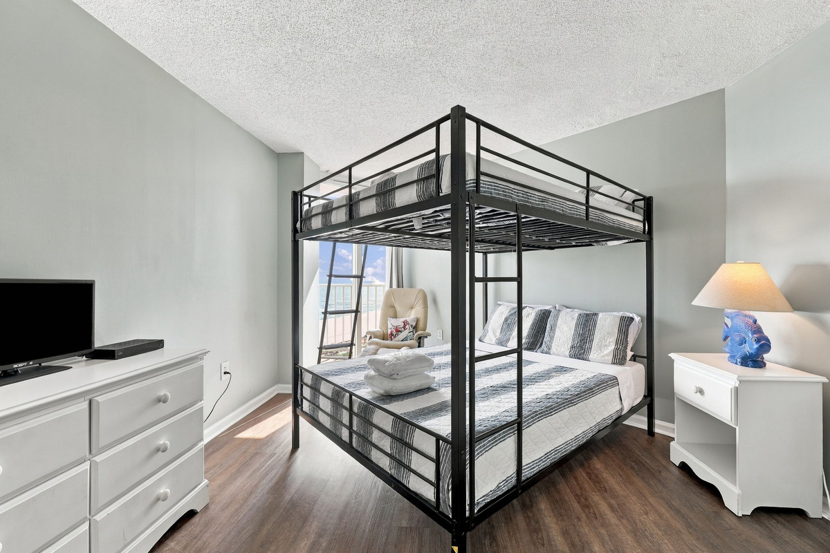 Spacious Queen-over-Queen bunk bed setup plus a dresser and TV.