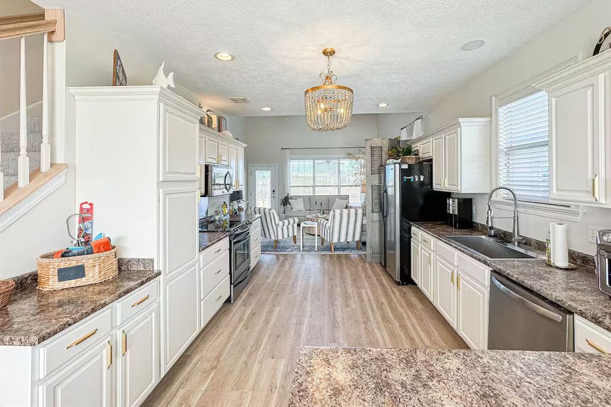 Spacious, sunlit kitchen featuring ample counter space, stainless steel appliances, and stylish lighting, perfect for cooking and entertaining.