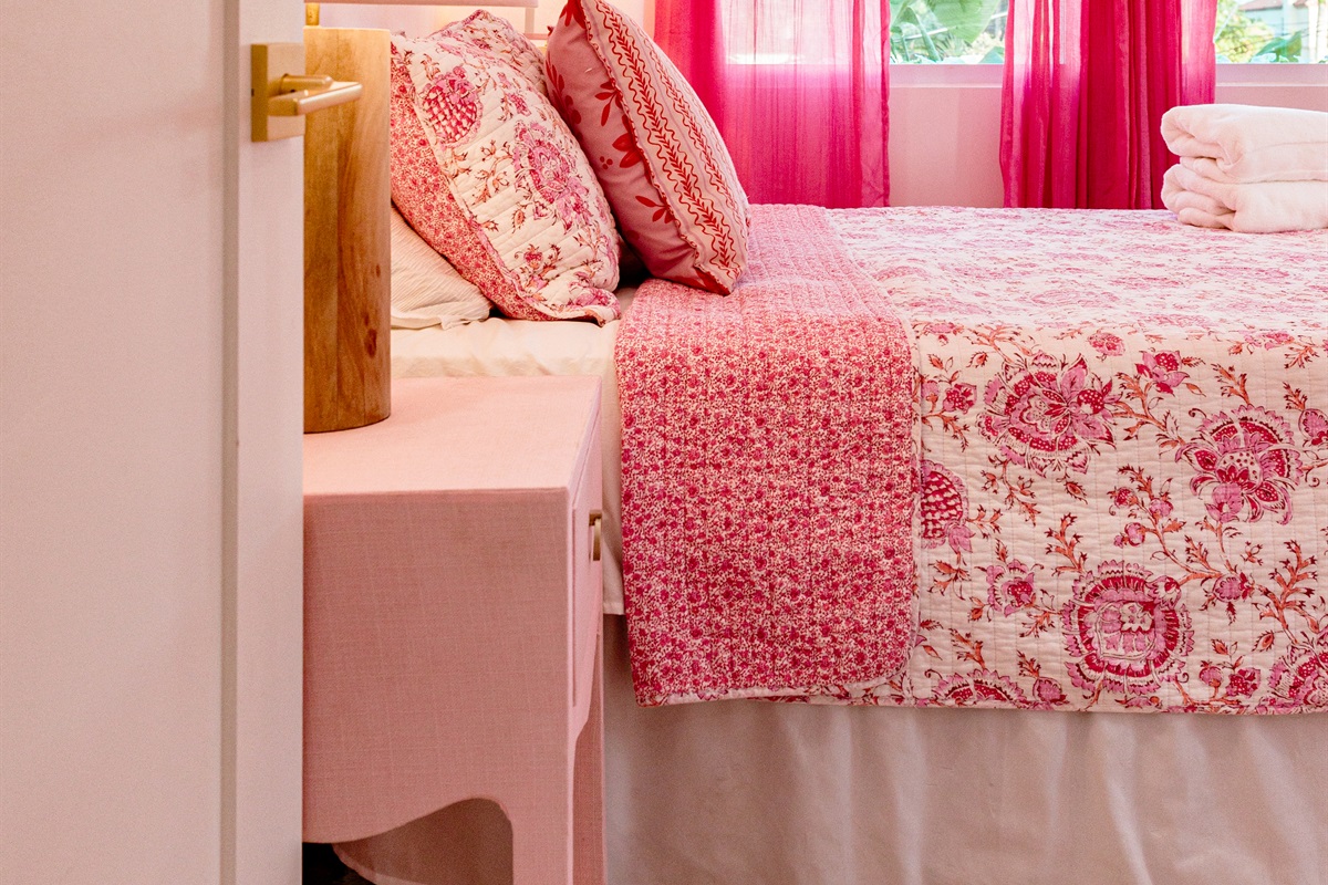 The second cottage bedroom is draped in themes of red and pink, a colorful and comfortable place to relax for a long evening's rest.