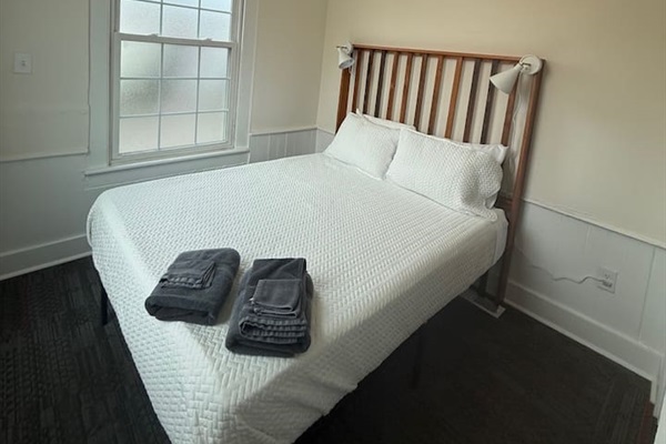 Cozy front bedroom featuring a queen bed, plush bedding, warm ambient lighting, and all the essential comforts for a restful stay.