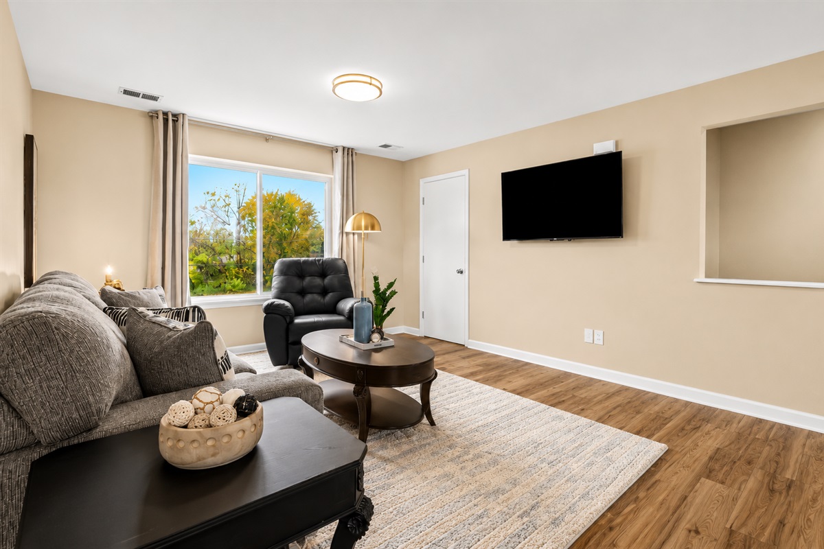 Relax in this bright and inviting living space featuring cozy seating, stylish décor, and a large smart TV perfect for movie nights or unwinding after a long day.