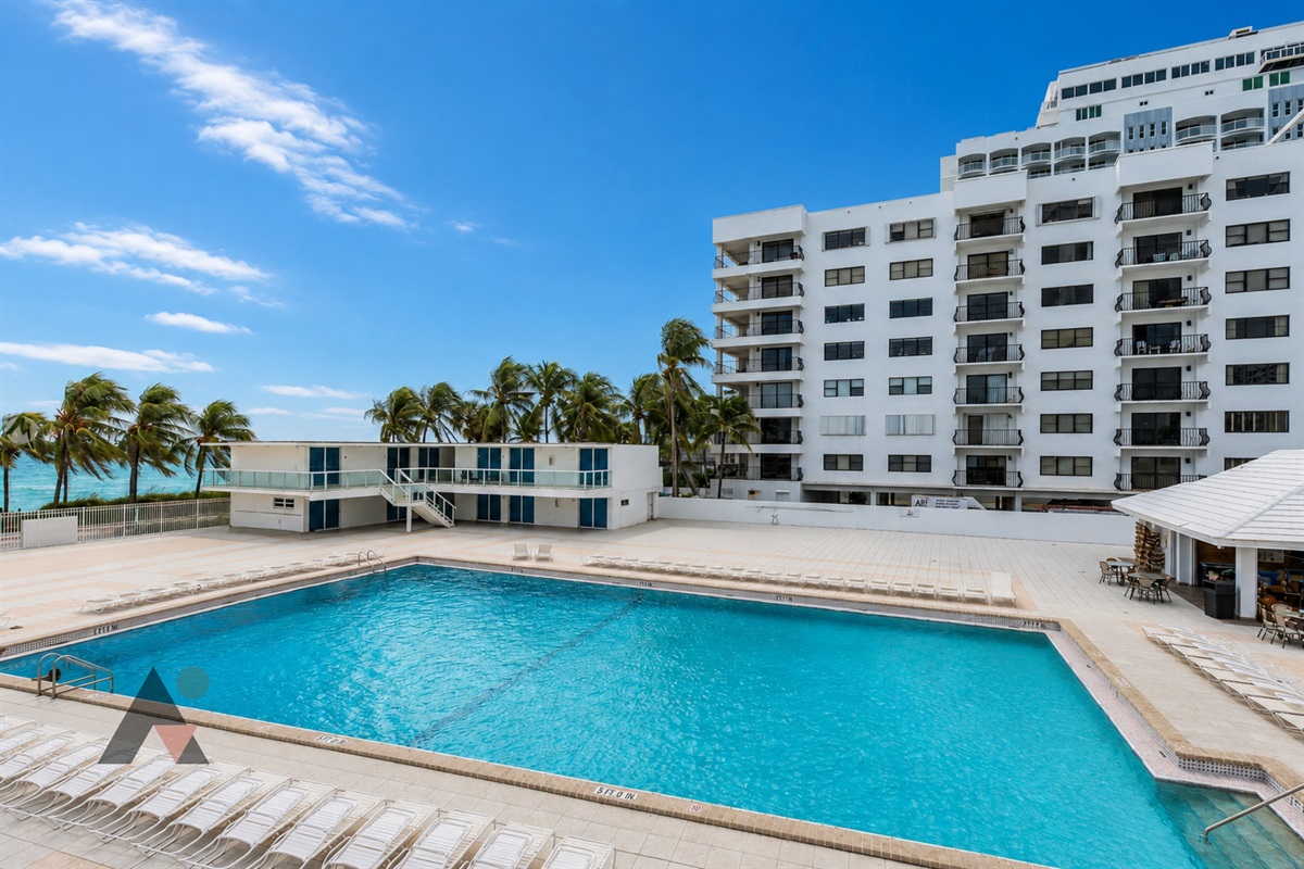 The expansive oceanfront swimming pool, surrounded by a sunny deck overlooking the beach.