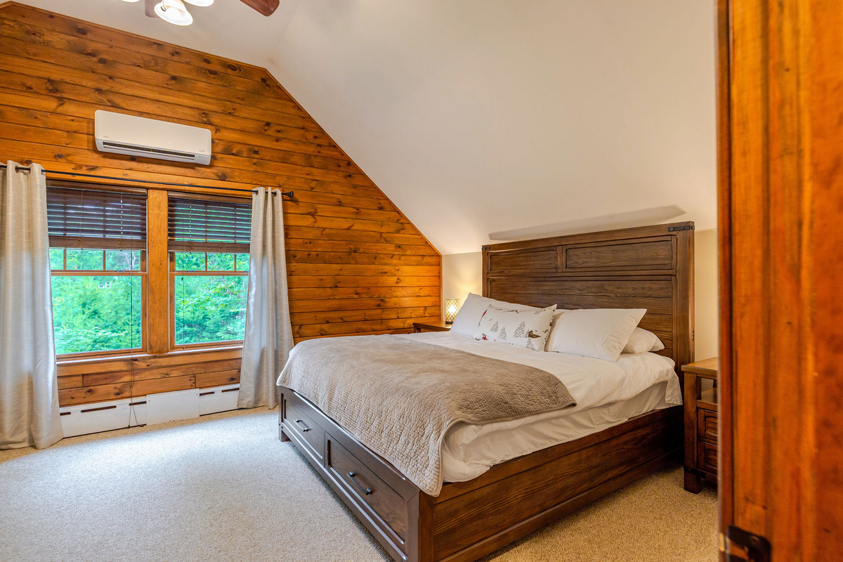 Bedroom 3 features a plush king bed, peaceful woodland views, and warm Adirondack charm—creating the perfect retreat after a day of hiking, skiing, or exploring.