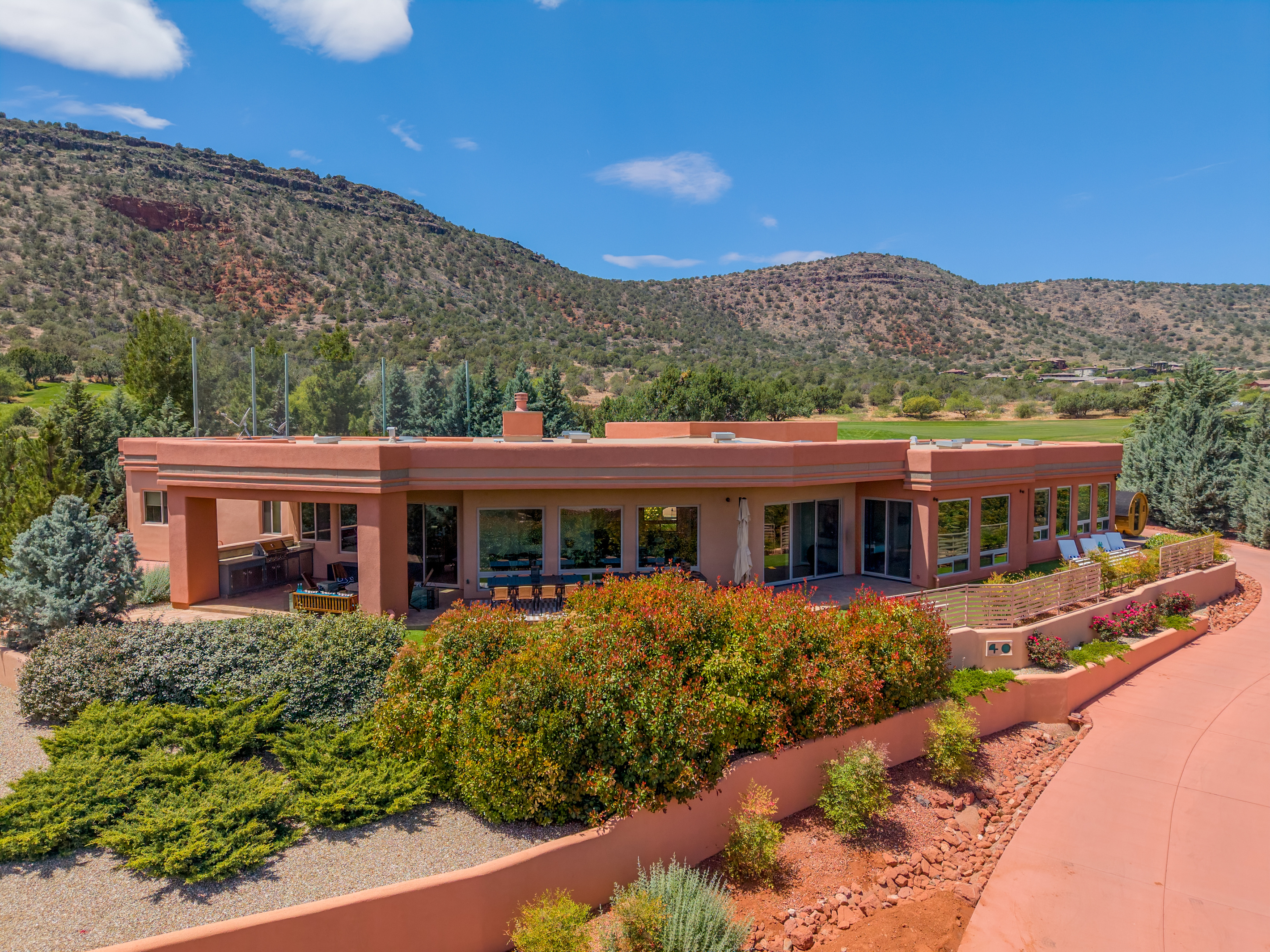 Spacious back patio with built-in outdoor kitchen, alfresco dining, and sun loungers set against golf course and mountain views.