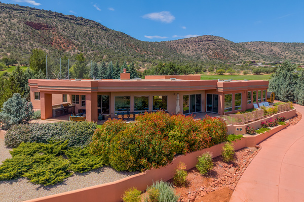 Spacious back patio with built-in outdoor kitchen, alfresco dining, and sun loungers set against golf course and mountain views.
