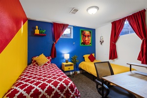 A bedroom adorned in a vibrant mix of red, yellow, and blue, illuminated by a cozy lamp for a lively and inviting atmosphere.