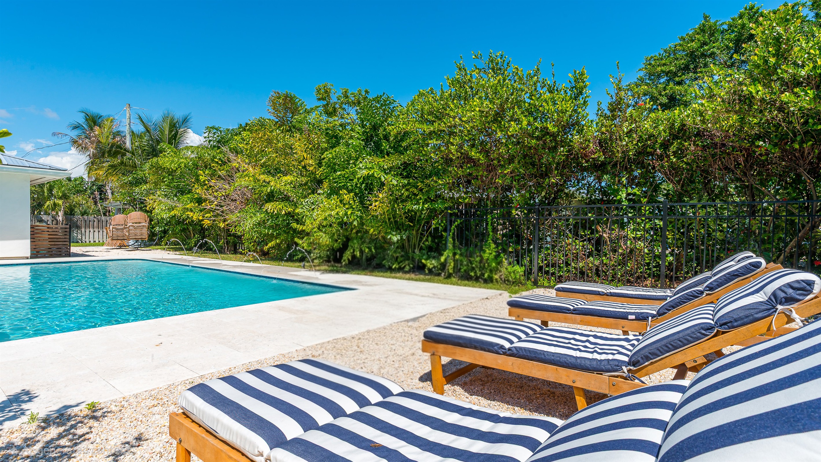 The pool deck is finished in shell white limestone, offering a beautiful natural backdrop.  By night, enjoy the tiki bar, TV, fire table, and the glow of the Jupiter Lighthouse Beacon 