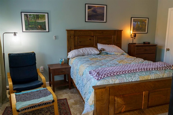 This is the bedroom with attached half bath. There is a reading chair, a bedside table, & chest of drawers. 