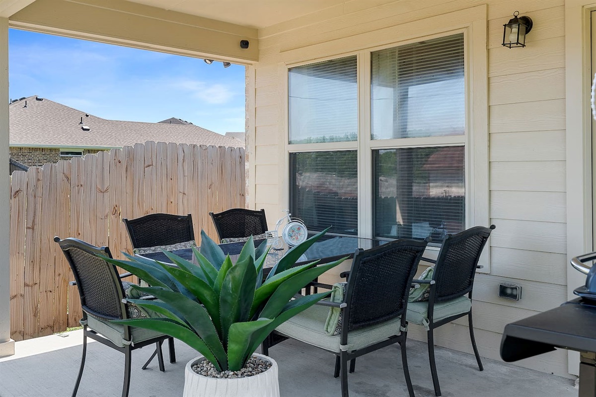 Enjoy a relaxing outdoor dining area with comfortable seating for 5 and a lovely potted plant.