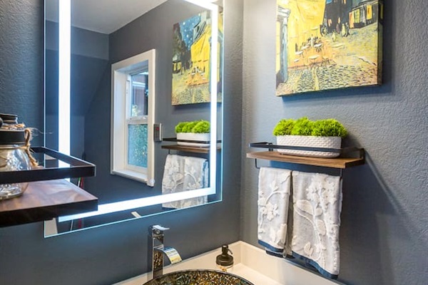 - Chic powder room with vessel sink and sleek illuminated vanity mirror  
- Dark accent wall and framed art create a sophisticated modern style  
- Floating shelves add both function and decorative touches to the space  
