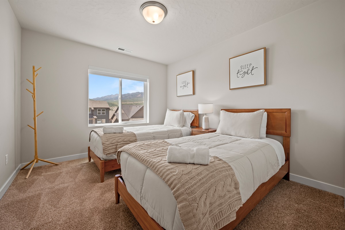 With plush linens, a coat rack, and sweeping mountain views, this twin bedroom combines comfort and charm in one relaxing space.