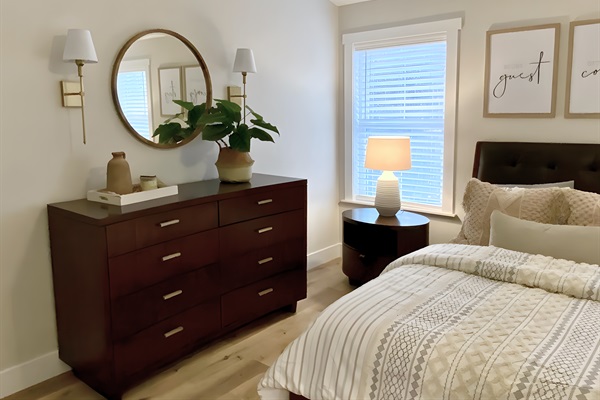 Relax in this cozy queen bedroom, featuring stylish decor and ample natural light. With luxurious linens, a spacious dresser, and thoughtful touches, it’s the perfect retreat. 