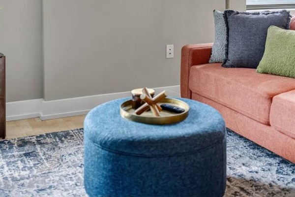 Relax in a chic living room with a coral sofa, plush pillows, bold abstract art, and a gold arc lamp. Designed for comfort and style, this inviting space is perfect for movie nights, remote work, or lounging between downtown adventures.
