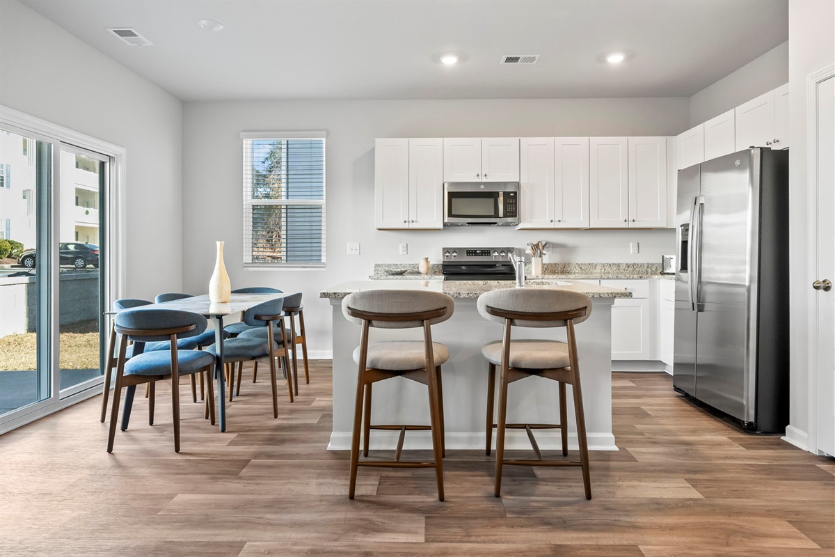 Modern kitchen with granite countertops and stainless steel appliances, dining room table seats 6