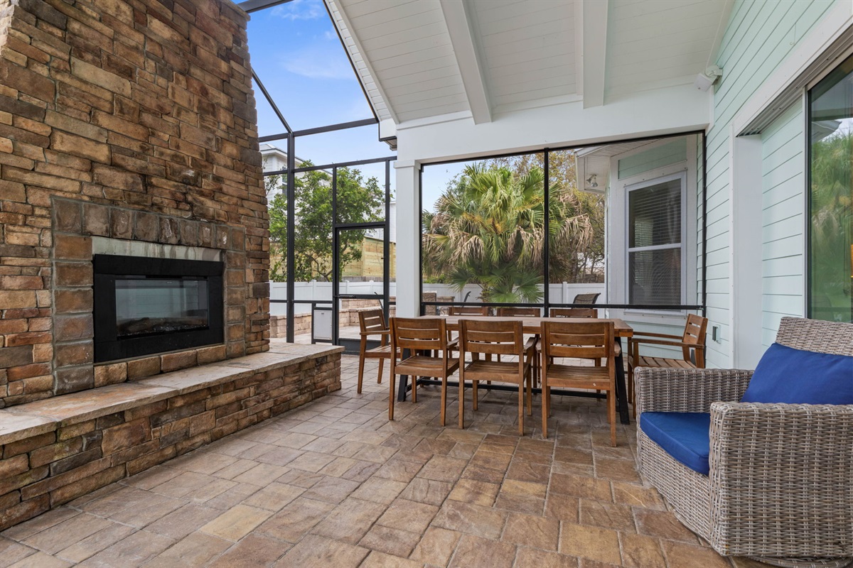 Gather for dinner under the covered lanai, linger by the outdoor fireplace, and let the night flow from patio to living room—blue-cushioned rockers, warm coastal air, and easy conversations that make vacation feel exactly right.