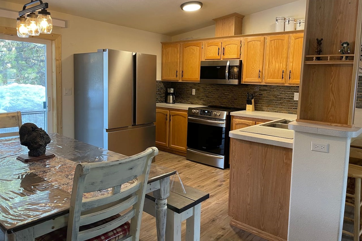 Kitchen with Updated Appliances, Backsplash, Faucet, Cupboard Door Handles, Light, Table, and Flooring