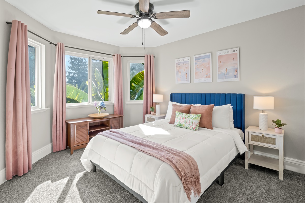 Bright, beautifully styled retreat featuring a statement headboard, designer accents, and sun-filled corner windows for a true vacation vibe.