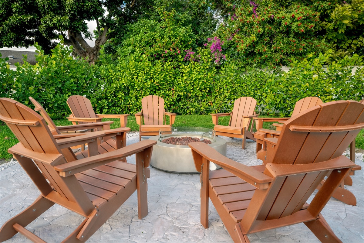 Gas-powered fire pit surrounded by Adirondack chairs in a private, family-friendly Palm Beach backyard.