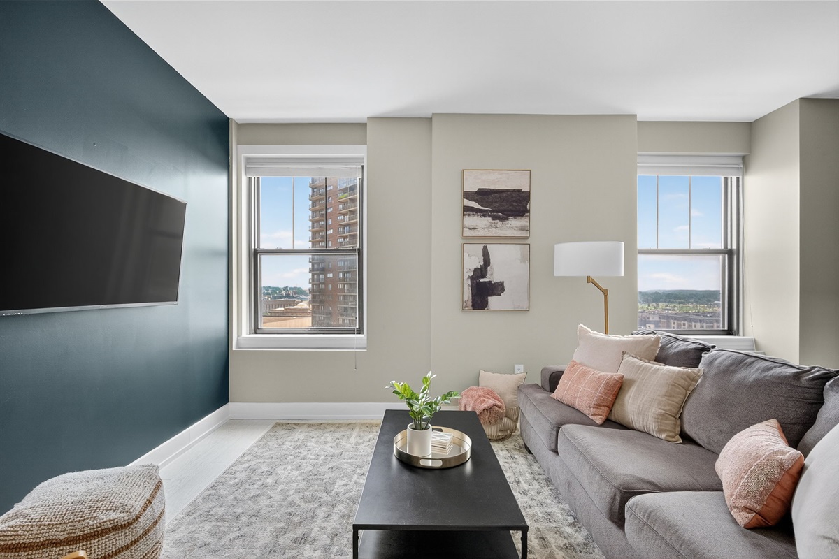 Relax in a stylish living room with a mounted flatscreen TV, curated decor, and a luxe accent wall.