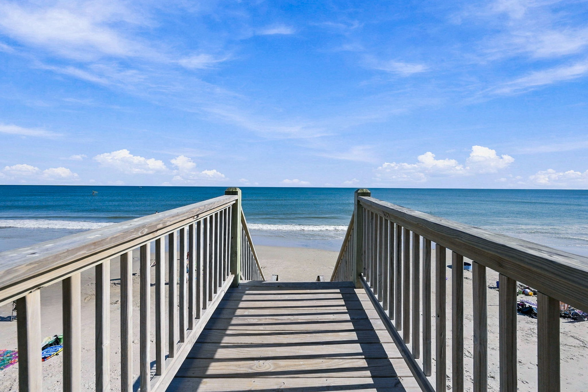 Private wooden boardwalk dune crossover offering seamless, direct access to the sandy beach and endless horizon views of the Atlantic Ocean.   