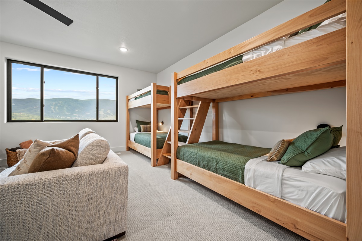 With ample sleeping arrangements, cozy seating, and a large window framing the mountain backdrop, this bunk room is both fun and functional.