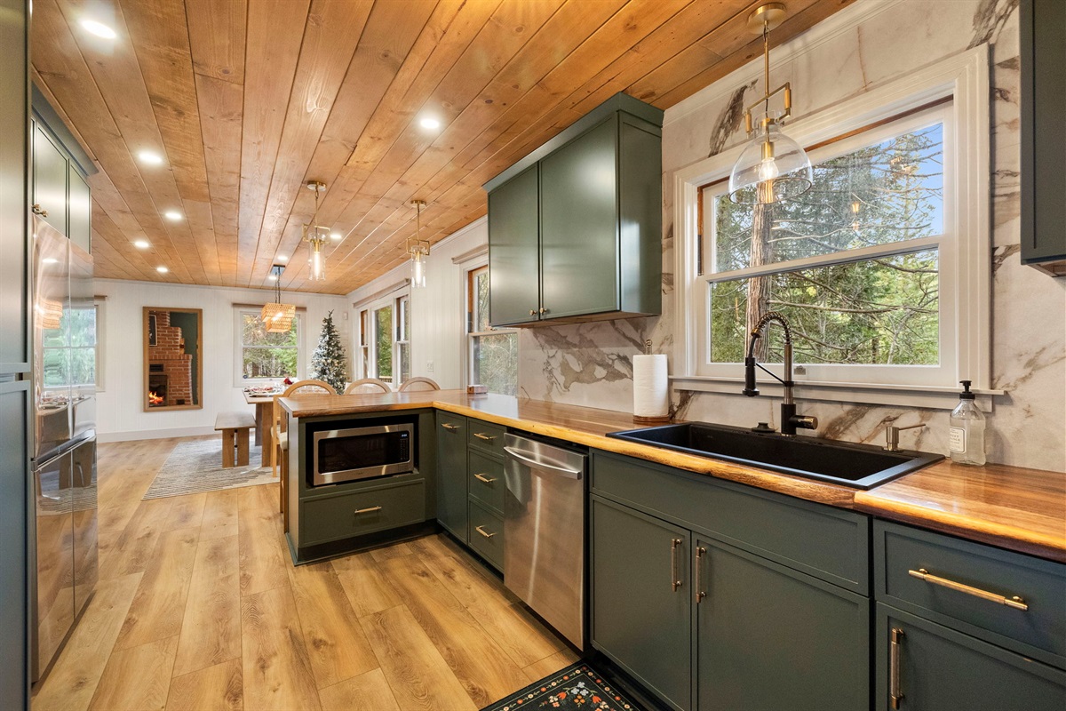 Beautiful views over the kitchen sink. Custom acacia, raw edge countertops showcase the kitchen.